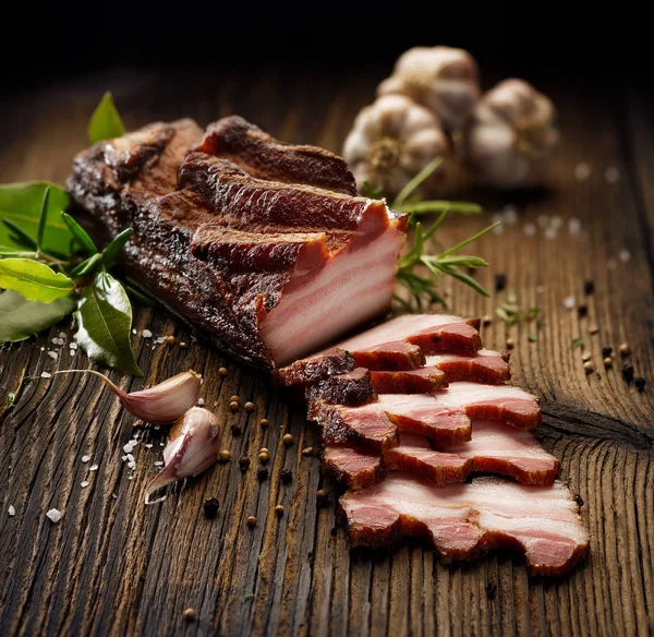 Geräucherter Speck Auf Einem Rustikalen Holztisch Mit Frischen Aromatischen Kräutern — Stockfoto