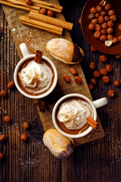 Varm choklad med vispgrädde beströs med aromatiska kanel i koppar på ett träbord, ovanifrån. — Stockfoto