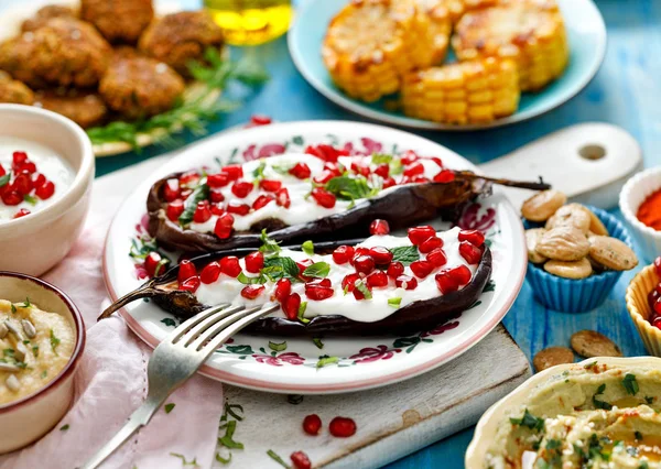 Grilled eggplant with yoghurt sauce, pomegranate seeds and fresh fresh herbs on a ceramic plate — Stock Photo, Image