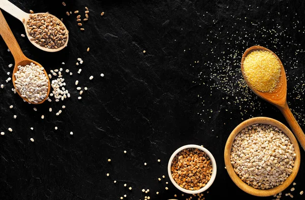 ひき割り穀物 穀物の様々 ひき割り穀物の鉢と黒の背景 上面にスプーンの種類 健康栄養食品 — ストック写真