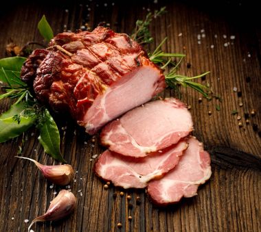 Smoked gammon on a wooden rustic table with addition of fresh aromatic herbs, top view.  Natural product from organic farm, produced by traditional methods clipart
