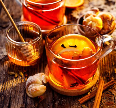 Zencefil, karanfil, tarçın ve portakal dilimleri, lezzetli, ısınma ve sağlıklı ahşap bir masa üzerinde cam bardak ile baharatlı narenciye sıcak çay