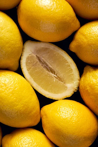 Fresh lemons on a black background, top view, close up