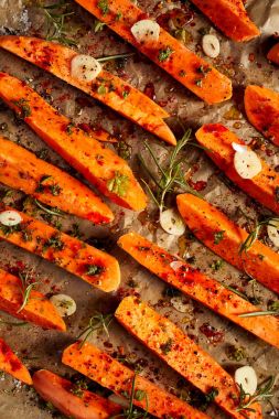 Otlar, sarımsak, deniz tuzu ve zeytin yağı pişirme kağıdı üzerinde en iyi görünüm için hazırlanan tatlı patates gelen ham patates kızartması terbiyeli