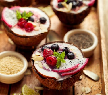 Berry güler yüzlü bir Hindistan cevizi kase taze Pitaya meyve (Dragon fruit), yaban mersini ve ahududu, nane, badem pul, chia tohum ve susam ile. Sağlıklı ve lezzetli tatlı veya Kahvaltı, vejetaryen yemek