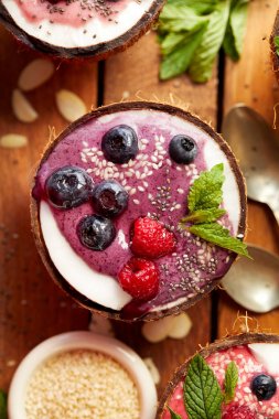 Berry güler yüzlü bir Hindistan cevizi kase taze yaban mersini ve ahududu, nane, badem pul, chia tohum ve susam ile. Sağlıklı ve lezzetli tatlı veya Kahvaltı, vejetaryen yemek