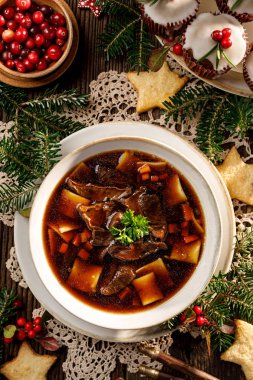 Noel mantar çorbası, geleneksel vejetaryen mantar çorbası. Kurumuş orman mantarlarından yapılmış. Şenlik masasında seramik bir tabakta. Polonya Noel yemeği