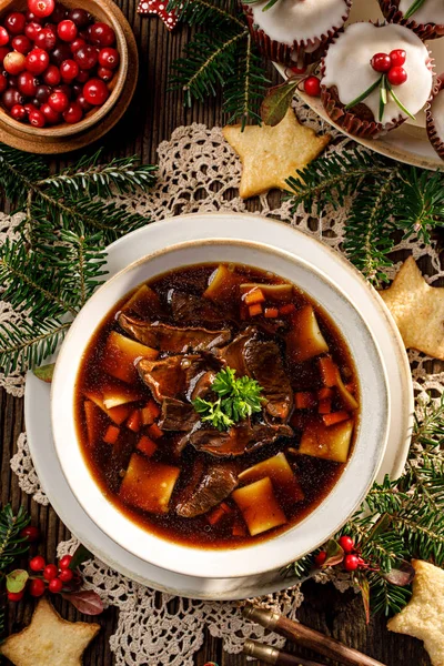 Christmas mushroom soup, a traditional vegetarian mushroom soup made with dried forest mushrooms in a ceramik plate on a festive table, top view. Polish Christmas dinner — Stock Image Christmas Mushroom Soup Traditional Vegetarian Mushroom Soup Made Dried Forest Royalty Free Stock Photos