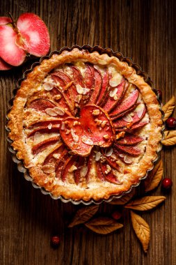 Elmalı tart, kırmızı elmalı tart, tarçın, badem gevreği ve bal, ahşap bir arka planda toz şeker serpiştirilmiş, üst manzara. Lezzetli bir ev yapımı tatlı.