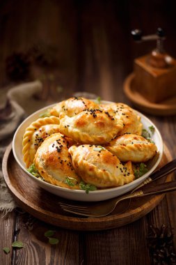 Hamur köftesi, ahşap bir kırsal masada seramik bir kasede mantarlı ev yapımı hamur köftesi (pierogi). Vejetaryen yemeği.