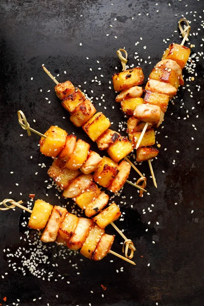 烤绞架 菠萝果和鸡肉洒有芝麻籽和香料在黑色背景 顶部视图 水果和肉类绞架 — 图库照片