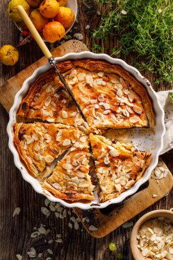 Peynir ve haşhaş tohumu turtası, ahşap bir kırsal masada badem ezmesi serpiştirilmiş tatlı tart, üst manzara. Lezzetli bir ev yapımı tatlı. 