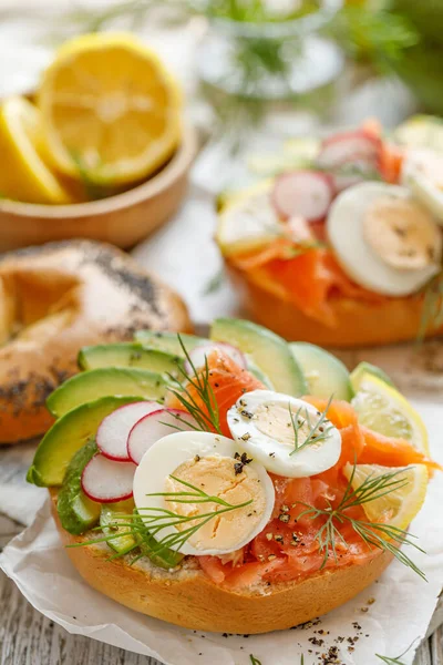 Sanduíche Bagel Com Salmão Defumado Abacate Cozido Ovos Rabanete Limão — Fotografia de Stock