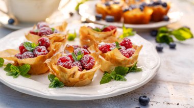 Mascarpone peynirli Phyllo bardakları taze ahududu ve beyaz bir tabakta nane şekeri ile kaplıdır. Lezzetli fileto pasta tatlısı