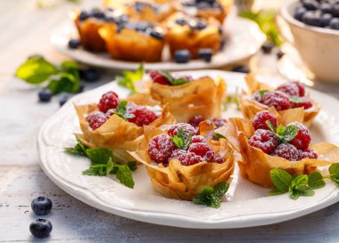 Mascarpone peynirli Phyllo bardakları taze ahududu ve beyaz bir tabakta nane şekeri ile kaplıdır. Lezzetli fileto pasta tatlısı