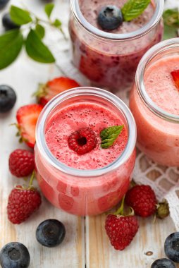 Cam kavanozlarda ahududu, yaban mersini ve çilekli meyve püresi.