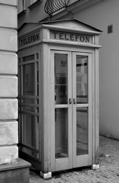 Old black and white telephone booth adorning the old streets of the city