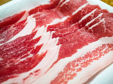 Beyaz tepside dilimlenmiş çiğ domuz pastırması. Mutfakta lezzetli yemekler yapmak için kullanılır. Yatay görünüm