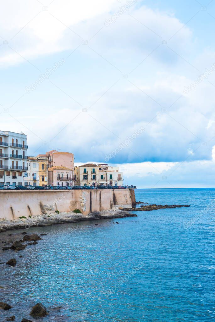 Wonderful view of the seafront of Ortigia in Syracuse on a summer day, with blue sea and cloudy sky as a background.