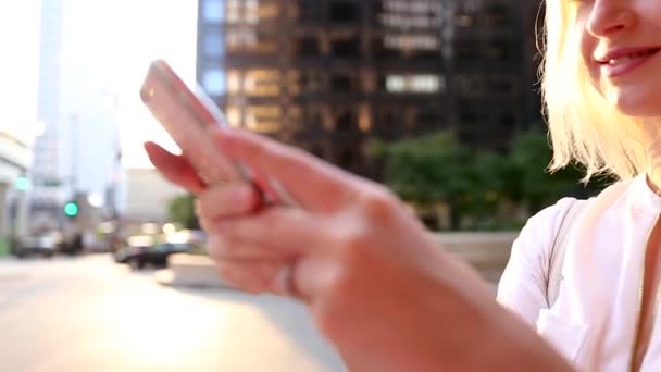 Una jovencita de pie en la calle, recibiendo un mensaje por teléfono y sonriendo . — Vídeos de Stock