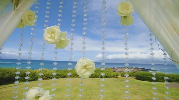Brillantes cuentas de cristal con rosas blancas en el arco de la boda a través de los rayos del sol de montaje resort kapalua en maui, hawaii — Vídeo de stock