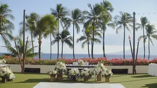 Декоративні квіти біля весільного столу новоспеченого на тлі красивої природи і блакитного океану на курорті гіатт, мауї, гаваї — стокове відео