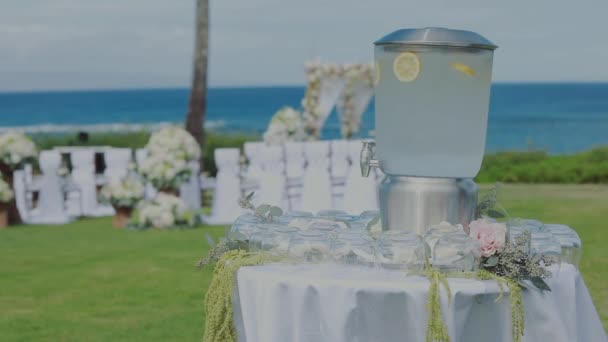 Tarro de cristal con bebida de limón tónico y vasos vacíos en la mesa en la celebración de la boda en el montaje del complejo kapalua, isla maui, hawaii — Vídeo de stock