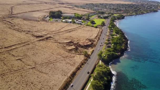 Vacker bild av vulkaniska landskap vid foten av berget mauna loa och väg med bilar i närheten av oceanshore i ön maui, hawaii — Stockvideo