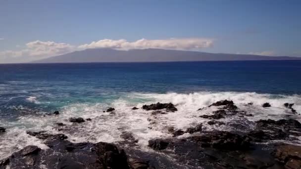 Привлекательный выстрел воды брызг против скал на фоне больших гор Мауна Лоа с субвоздушным вулканом в облаках на Мауи, Гавайи — стоковое видео
