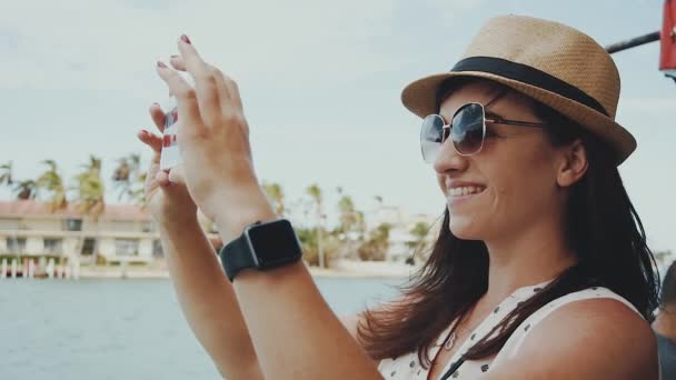 Vackra leende flicka i glasögon och hat att göra foto på telefon på bakgrunden av tropisk natur sunny isles beach, miami — Stockvideo