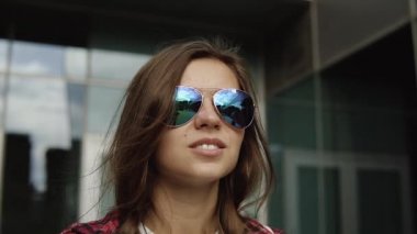 ayna duvarlar ile modern building yakınındaki Kahverengi saç ve moda gözlüklü genç kadın hayal