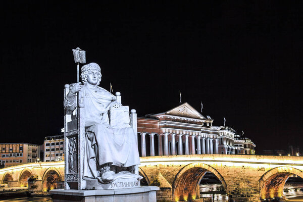 Monument to Justinian the First against the backdrop of the Stone Bridge and the Archaeological Museum in Skopje, Macedonia