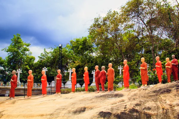 Een reeks van beelden van boeddhistische monniken in oranje tinten in een boeddhistische tempel in Sri Lanka — Stockfoto