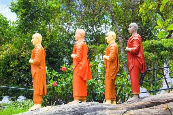 Een reeks van beelden van boeddhistische monniken in oranje tinten in een boeddhistische tempel in Sri Lanka — Stockfoto