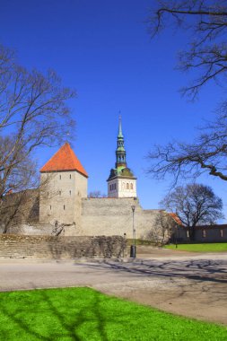 Güzel bir kız Kulesi bitişik kalenin duvar ve kubbe Oleviste Churchand Tallinn, Estonya-güneşli bir kulenin manzarası
