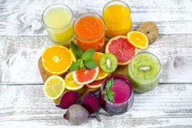 Tahta arka planda cam şişelerdeki meyve ve sebzelerden taze detoks sıvıları.
