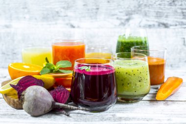 Tahta arka planda cam şişelerdeki meyve ve sebzelerden taze detoks sıvıları.