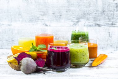 Tahta arka planda cam şişelerdeki meyve ve sebzelerden taze detoks sıvıları.