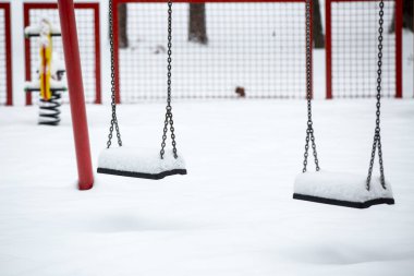 Kışın kar altında salıncaklı bir çocuk parkı