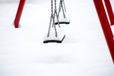 Kışın kar altında salıncaklı bir çocuk parkı