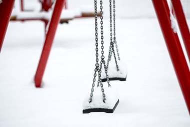 Kışın kar altında salıncaklı bir çocuk parkı