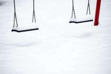 Kışın kar altında salıncaklı bir çocuk parkı