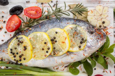 deniz levreği sebze ve baharat beyaz ahşap zemin üzerinde