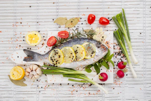 Sea bass with vegetables and spices on white wooden background — Stock Photo, Image