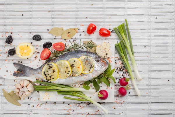 Sea bass with vegetables and spices on white wooden backgroundsea bass with vegetables and spices on white wooden background — Stock Photo, Image