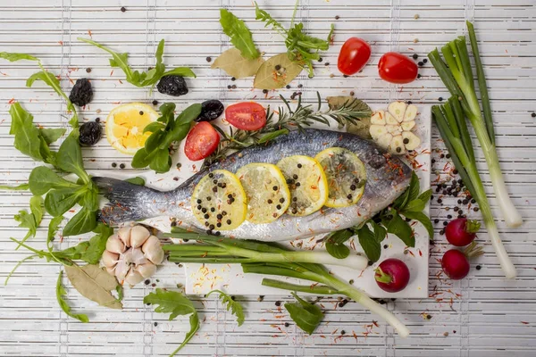 Sea bass with vegetables and spices on white wooden background — Stock Photo, Image