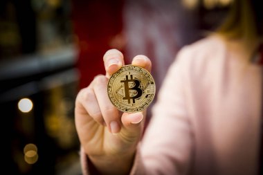 bir kadının elinde altın bitcoin