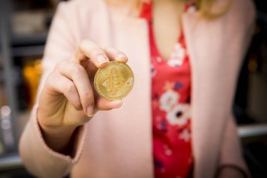 bir kadının elinde altın bitcoin