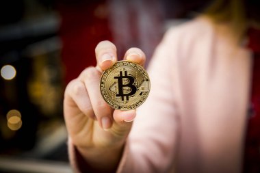 bir kadının elinde altın bitcoin