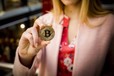 bir kadının elinde altın bitcoin